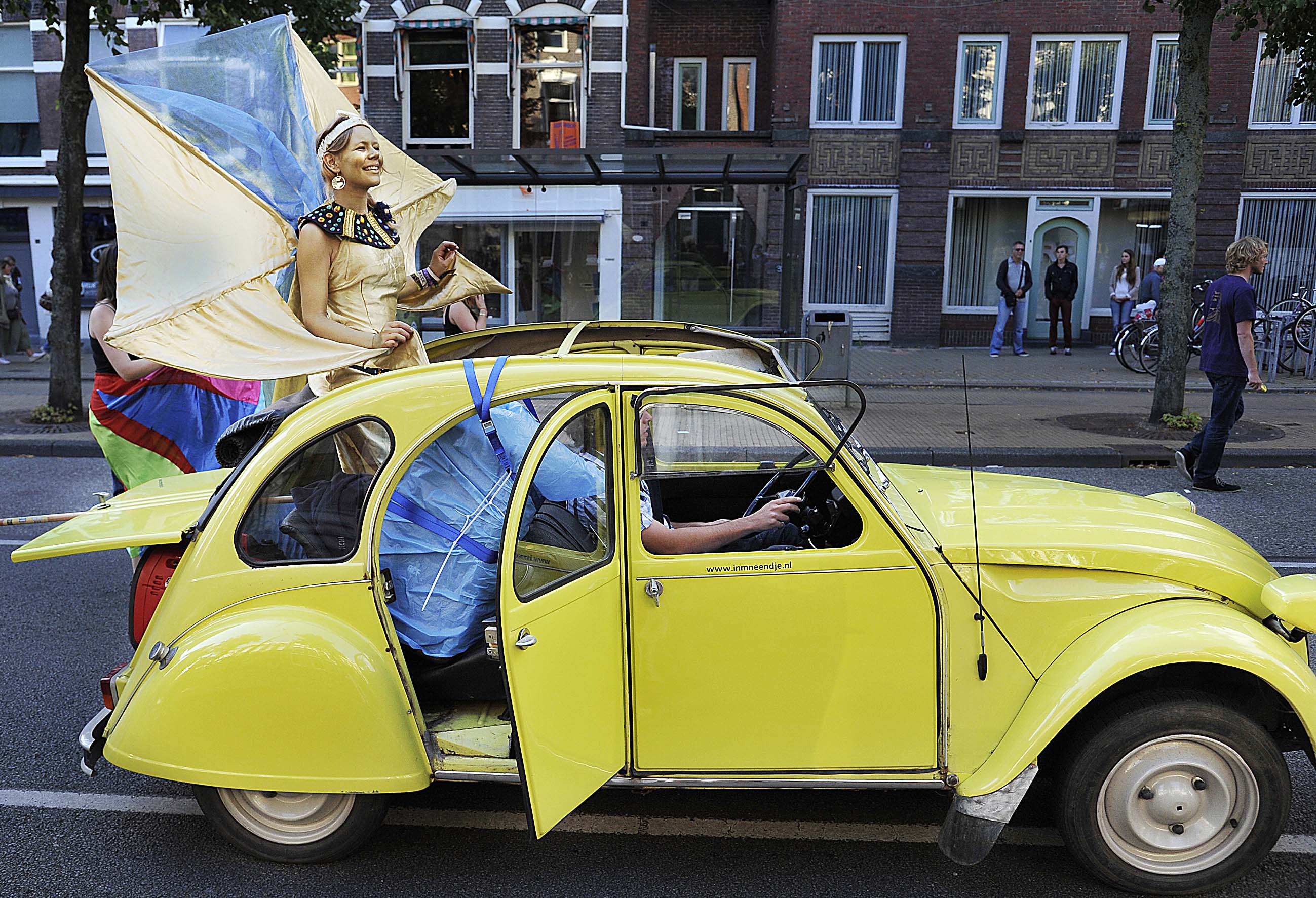13 augustus 2013: Studenten van Cleopatra in een knettergele deux-chevaux op het Zuiderdiep tijdens de KEI-parade.