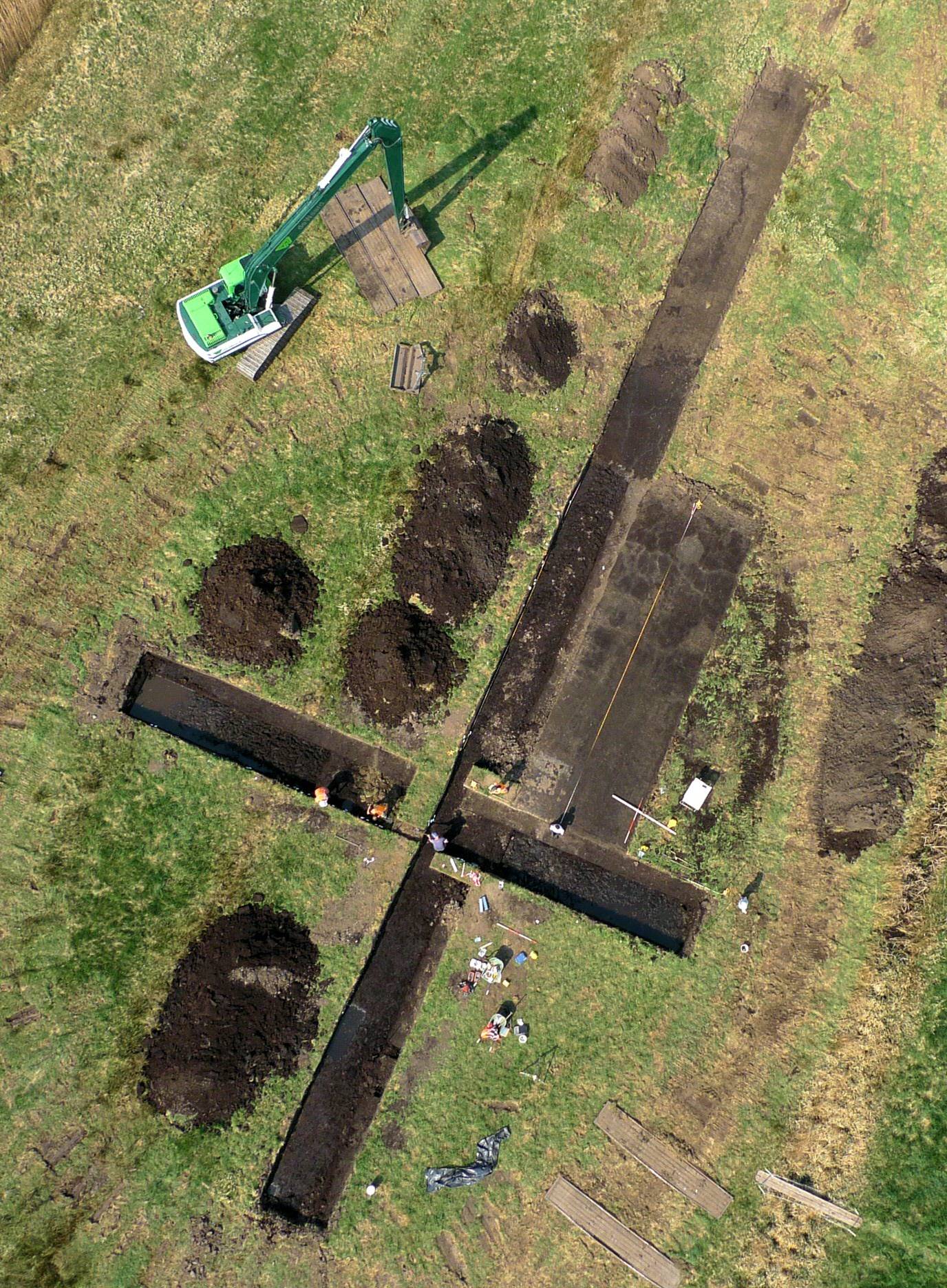 Vliegerfoto van één van de laatmiddeleeuwse huisplaatsen in De Onlanden, die door archeologen is onderzocht. Over de huisplaats is een kruis van sleuven gegraven, zodat sporen van een woonhuis en enkele waterputten zichtbaar worden (© E. Kieboom).